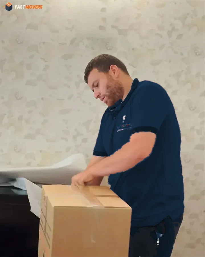 عامل يغلق كرتونة بالشريط اللاصق