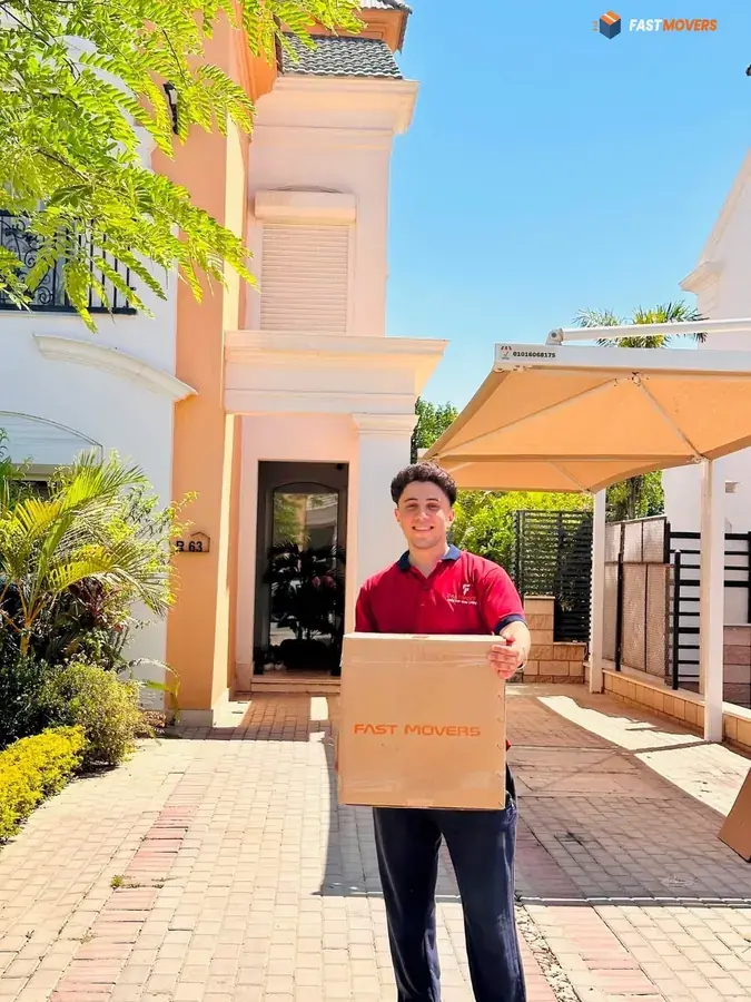 عامل Fast Movers يحمل كرتونة أمام فيلا